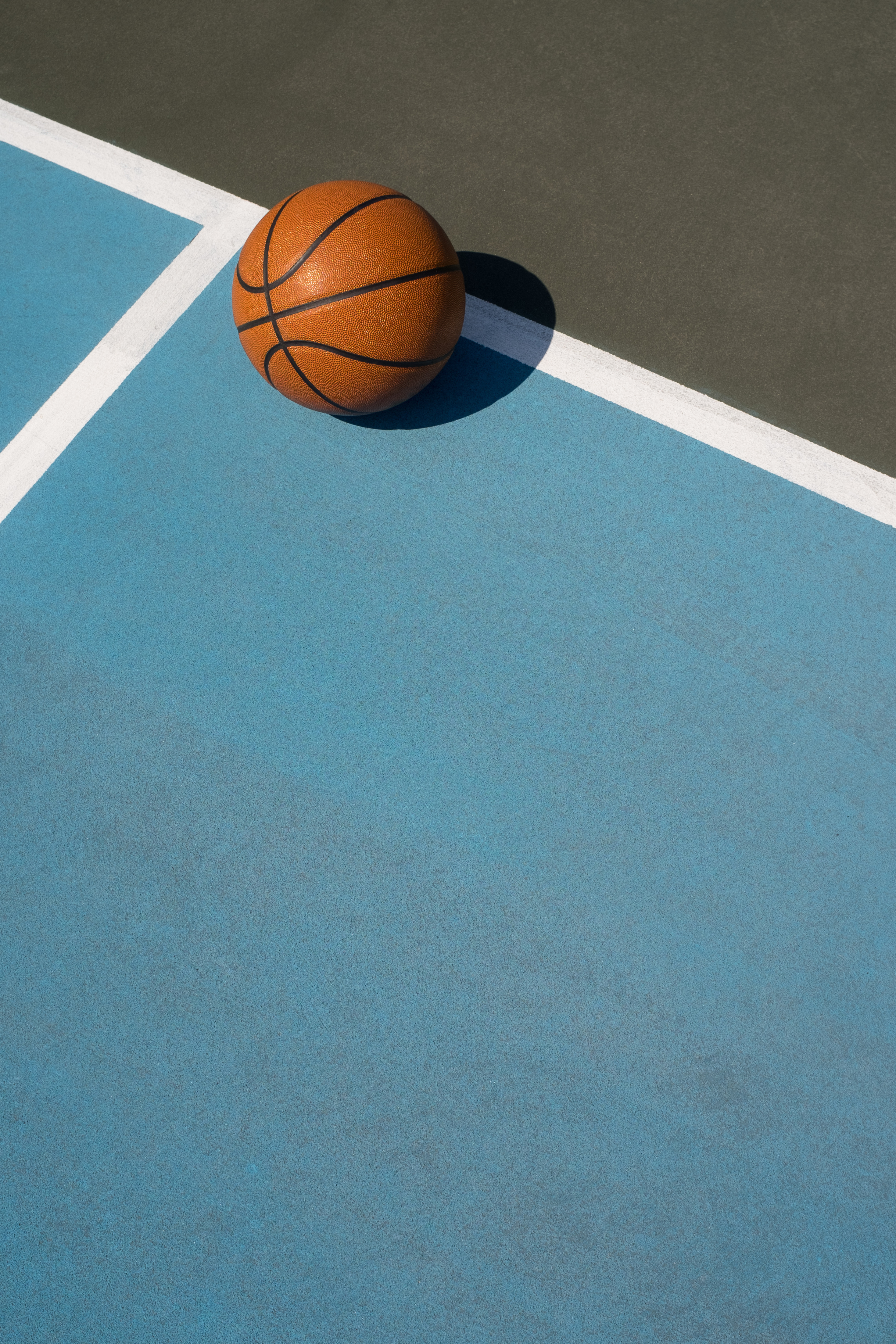 Basketball on outdoor court in sun